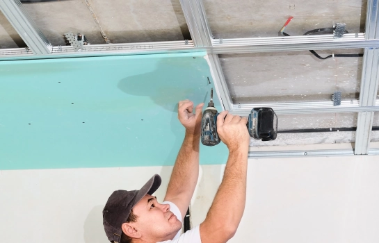 worker using drill machine to fix ceiling drywall screws – Buildwell