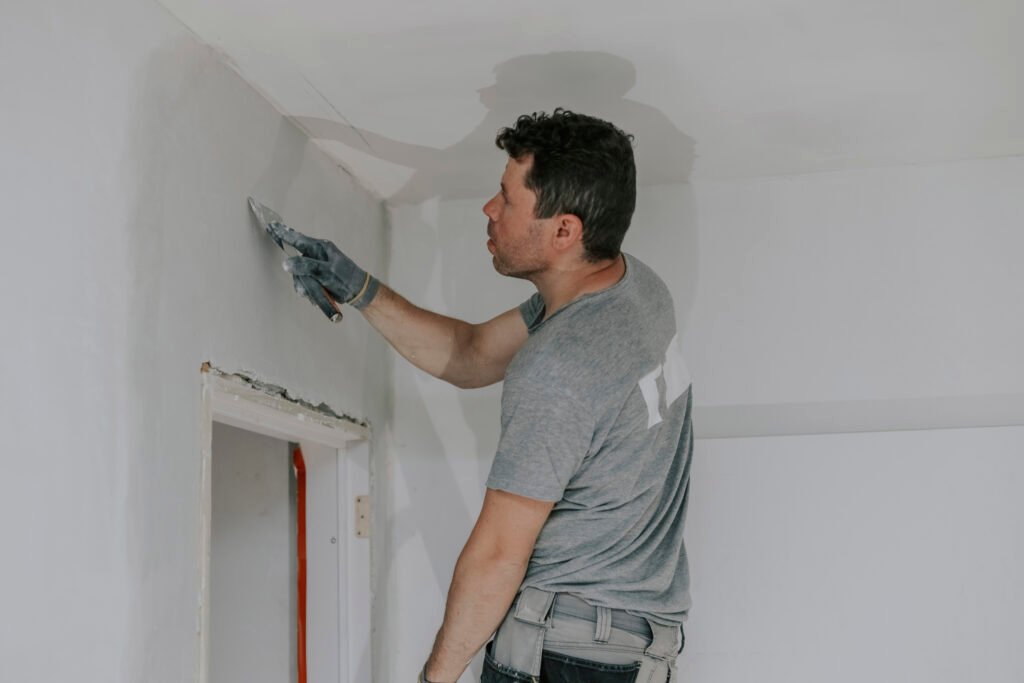 Worker applying gypsum bond on ceiling for strong adhesion and smooth plaster finish