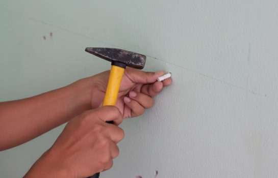 person inserting Buildwell plastic wall plug into wall using hammer – Buildwell