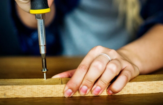 worker fixing screw with Buildwell manual screwdriver on wooden surface – Buildwell