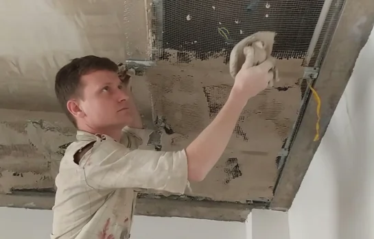 Worker installing ceiling plaster using wire mesh for better grip and surface strength